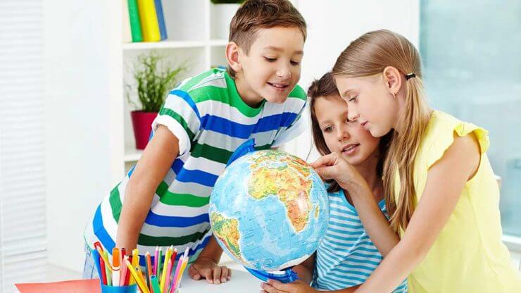 happy kids in a geography class near a globe
